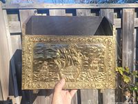 Front angled view of the wooden record holder showing brass embossed panel with sailing ships maritime scene
