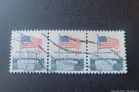 Front view of the block of 3 American flag stamps showing the detailed graphics, denomination, and cancellation marks.