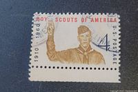 Front side of the vintage Boy Scouts of America 50th Anniversary stamp showing the Scout in uniform and cancellation marks.