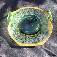 Top-down angled view showing the octagonal uranium glass dish with embossed design, gold rim, and two handles.