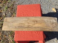 Top view of a rectangular live edge pine board laid flat on a red cloth with visible wood grain and natural markings.