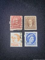 Four vintage Canadian stamps on black background showing different portraits and denominations.