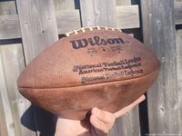 Photo of the football showing Wilson brand, National Football League and American Football League markings on the side.