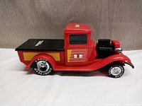 Side view of red vintage style Tonka toy truck showing the full body, flatbed, and racing tires.