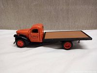 Side view of the orange and black scale model flatbed tow truck with Ajax Towing Service logo on cab door.