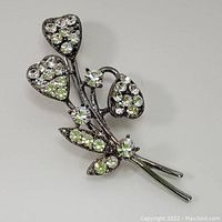 Front view of the floral crystal brooch showing three flower heads and leaves adorned with clear stones.