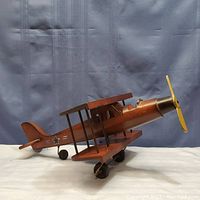 Side view of the wooden biplane model showing the shape, propeller, wheels, and star decal on the tail.