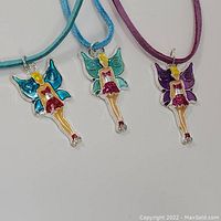 Three enameled fairy Tinkerbell pendants on colored fabric cord necklaces laid out flat