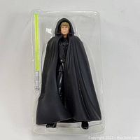 Luke Skywalker action figure posed in plastic tray alongside lightsaber accessory