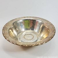 Front side view of sterling silver bowl showing wide rim with decorative pattern and inner base with embossed ring.