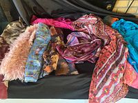 Photo showing various scarves in different colors, patterns including pink fluffy textured, floral patterned, and geometric motif scarves.