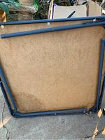 Underside of the foldable card table showing metal frame and wooden base with wear and discoloration.