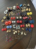 Photo of a variety of costume earrings arranged on a flat surface, featuring multiple colors and styles.