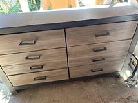 Front and side view image showing the six drawer wooden dresser with metal handles and visible damage on one drawer.