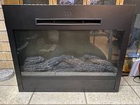 Front view of black electric fireplace insert with glass front, displaying artificial logs inside.
