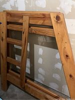 Side view of the upper bunk rail and ladder section made of pine wood with visible grain and knots.