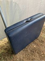 Closed view of blue leather-covered massage table showing carrying handle and fold line.