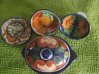 Top-down view of four Mexican pottery pieces with lids and a mug, displayed on green textured surface.