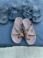 Top view of three pairs of sandals on black cloth background showing details of straps and footbeds.