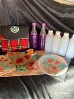 Main overview photo showing bottles, blanket, wine stoppers, bottle opener, and paper tableware.