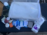 Full view of all items showing Therapedic pillow and various small wellness and personal care items including stress balls, mirrors, soap dish, cotton squares, laundry filters, and bottled water.