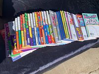 Photo showing a large collection of colorful Dell Puzzle Lovers word search and word find puzzle books laid out horizontally.