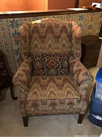 Front view of wing back chair showing patterned upholstery and matching throw pillow on seat.