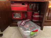 Interior shot of cabinet showing storage boxes with plates, bowls, mugs and a clear tub at floor level.