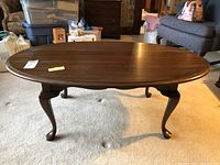 Oval wood coffee table with curved legs, view from above showing the tabletop.
