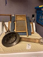 Vintage wooden washboard, black metal funnel tool with wooden handle, and flexible ribbed dryer mat hose on a table.