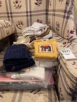 Stack of assorted folded linens and hand towels on patterned sofa upholstery featuring floral embroidery.