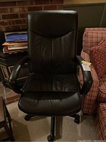 Front view of black swivel office chair showing padded backrest, armrests, and seat.