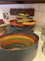 Two sets of nested oval wooden boxes stacked to show varying sizes and painted colors