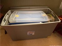 Large grey plastic storage container with smaller containers inside and lids, including blue lid with yellow clips and clear containers.