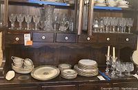 Overall view of middle cabinet shelf with crystal glassware and section of table level showing porcelain dishes