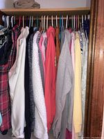 Full closet view showing mixed women's clothing including sweaters, sweatshirts, and vests hung on hangers.