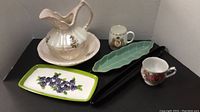 Overall view of washstand pitcher and bowl with platters and mugs on black surface