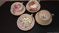 Four cups and saucers arranged on black surface showing each set