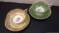 Overview of both Paragon bone china cups and saucers showing one green set and one cream set