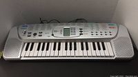 Full front view of Casio SA-75 electric keyboard showing keys, built-in speakers, and control panel.