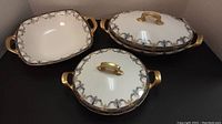 Three pieces shown: oval and round covered casserole dishes and a bowl, all with gold accents.