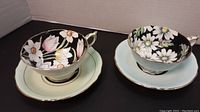 Two Paragon teacups and saucers side by side on black surface