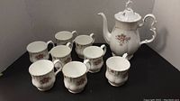 View of 8 Royal Albert Tranquility pattern coffee mugs arranged together, showing floral design and silver trim.