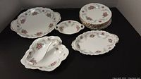 Overview of all plates and serving dishes in Royal Albert Tranquility pattern showing floral motifs and gold detailing.