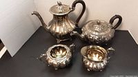 Full view of all four pieces - coffee pot, teapot, sugar bowl, and creamer arranged on a black surface