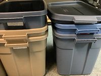 Four plastic storage bins stacked and showing their lids and handles; two beige and two blue bins included.