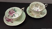 Two tea cup and saucer sets displayed side by side on black background