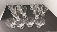 Full set of vintage etched glasses with distinctive circular dot pattern and beaded bases, including 6 wine, 6 water, and 4 sherbet glasses arranged on a dark surface.