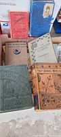 Full view of seven antique hardcover books showing titles, colors and general condition.