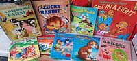 Top view of 9 vintage children's books with colorful cartoon and animal covers including The Flintstones, Lucky Rabbit, Berenstain Bears, Woody Woodpecker, and farm animals.